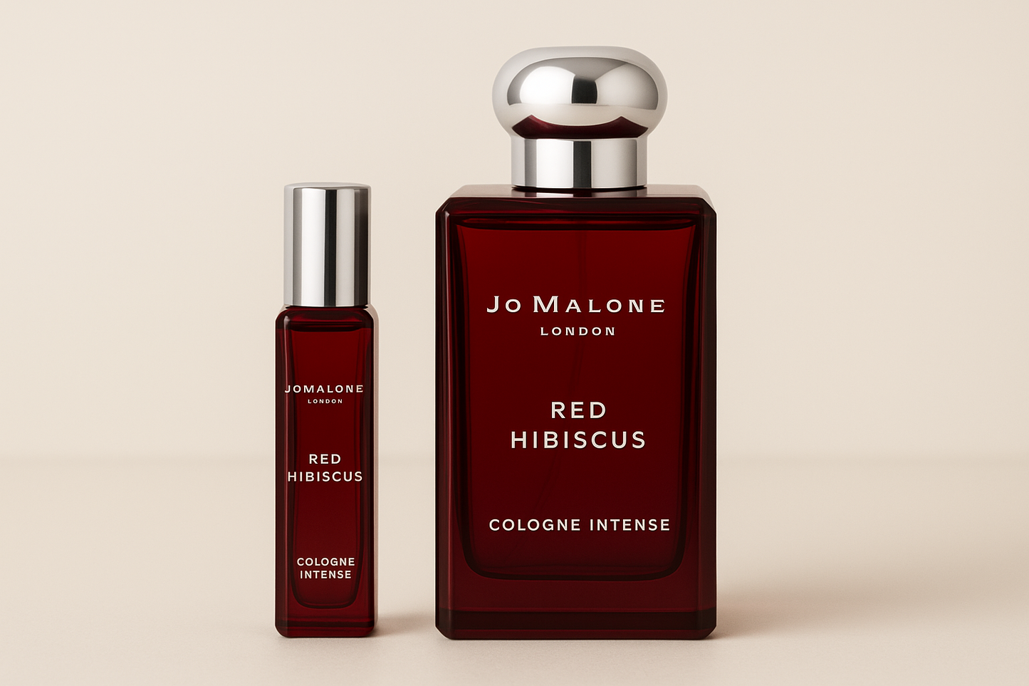 Jo Malone Red Hibiscus Cologne Intense 12ml 샘플이 진한 빨간색 병에 흰색 글씨가 적힌 Jo Malone Red Hibiscus Cologne Intense 100ml 향수병 옆에 서 있습니다.